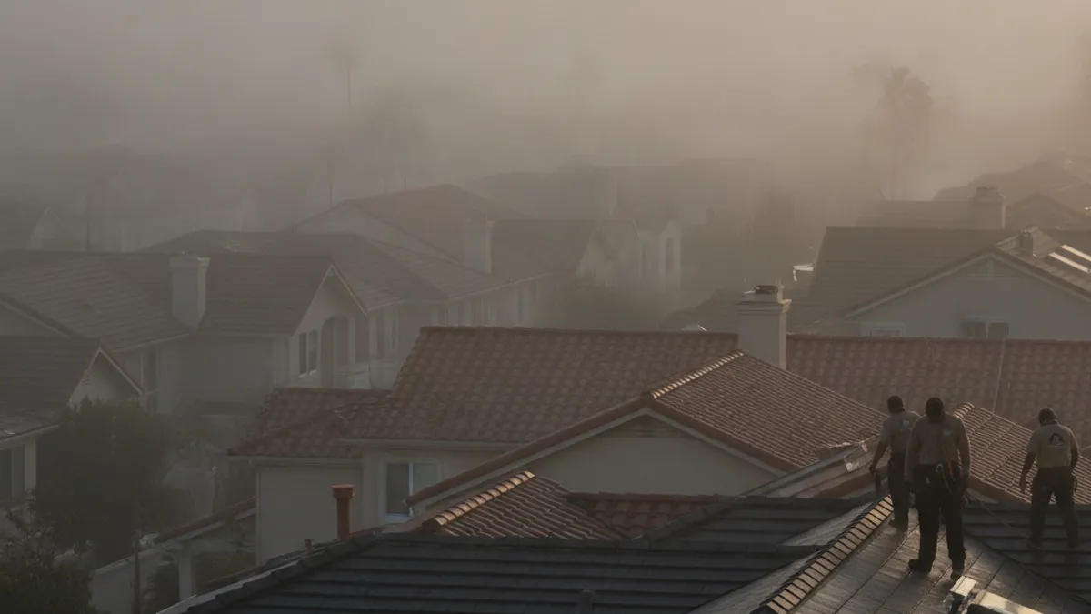 Thick marine layer fog rolling over a coastal San Diego neighborhood at dawn, condensation visible on rooftops